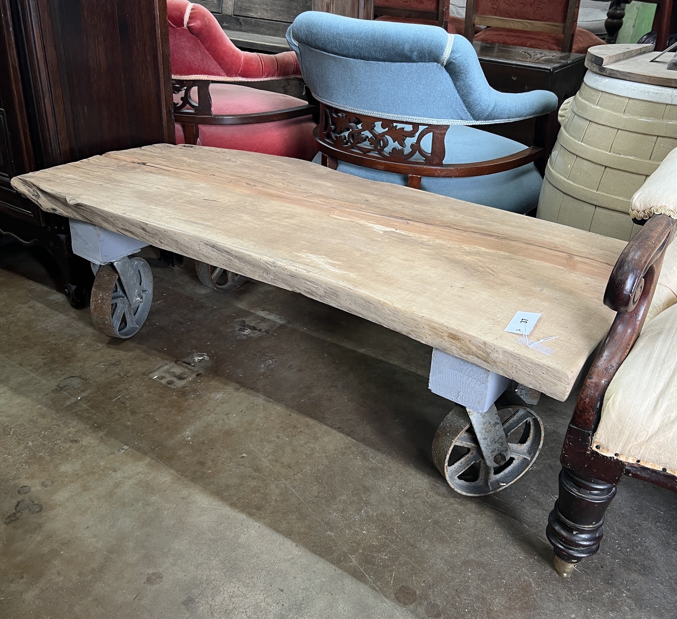 An industrial style rectangular waney edge plank top coffee table on spoked wheel base, width 122cm, depth 53cm, height 39cm